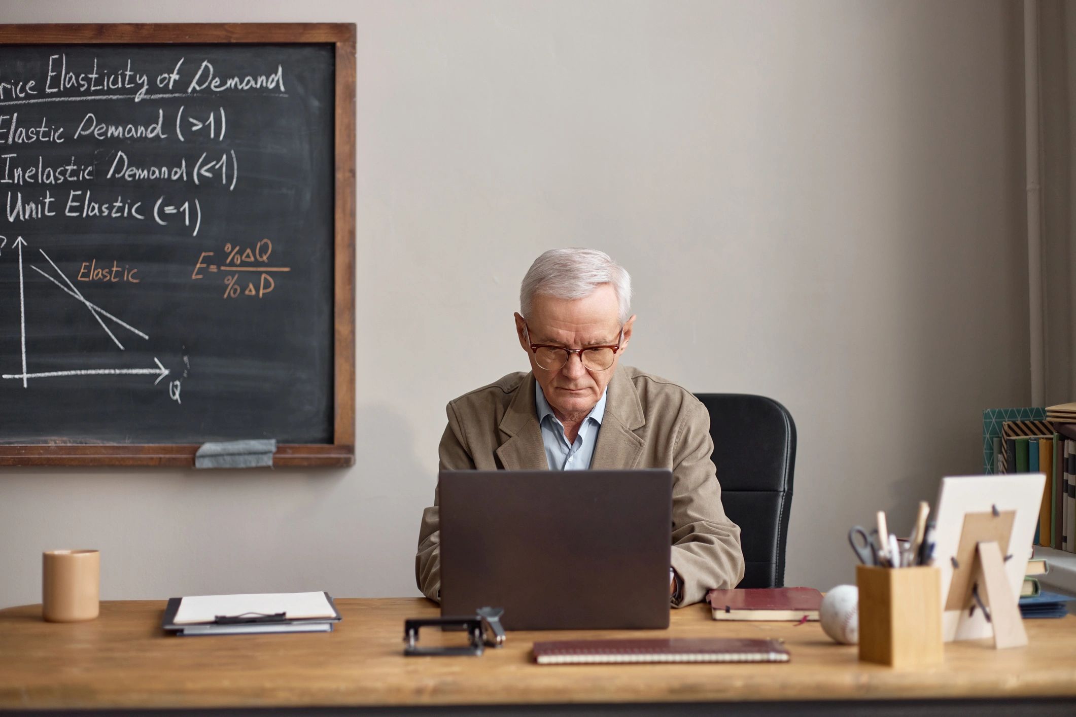 Scholar working thoughtfully at a desk with books and laptop